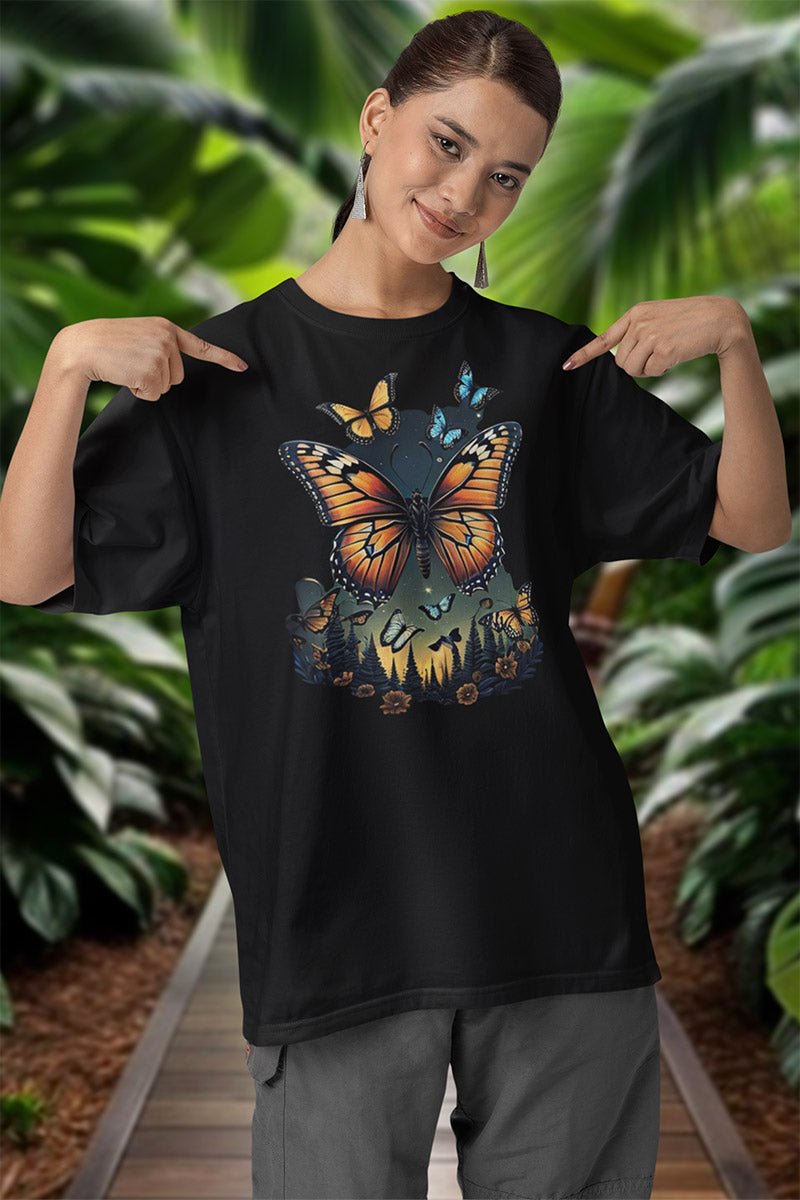 Frau zeigt mit beiden Händen auf das Shirt „Monarch Night“, Monarchfalter und hellblaue Falter